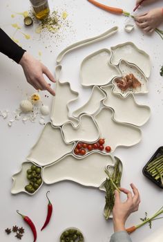 several people are working on a map made out of plates and vegetables, including carrots