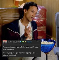 a man sitting in a chair holding a bowl of popcorn and pointing to the side