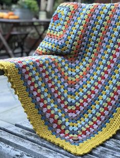 a crocheted blanket sitting on top of a wooden bench