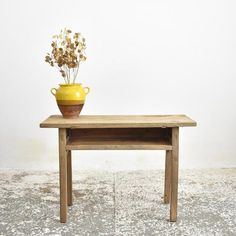 a small wooden table with a yellow vase on top