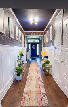 the hallway is decorated with floral wallpaper and colorful rugs on the hardwood floor