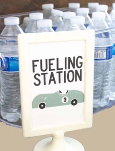 there is a sign that says fueling station with water bottles in the back ground