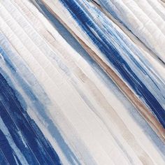 an unmade bed with blue and white stripes on it's coverlet, next to a pillow