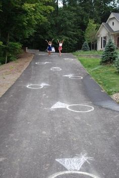 two people standing on the side of a road with arrows painted on it and one person holding up their hands