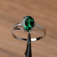 a ring with a green and white stone in it sitting on top of a wooden table