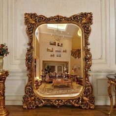 a large mirror sitting on top of a wooden floor next to a vase with flowers