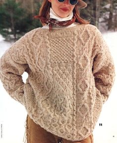 a woman standing in the snow wearing a sweater and hat