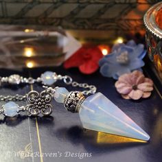 a close up of a bracelet with charms and beads on a table next to flowers