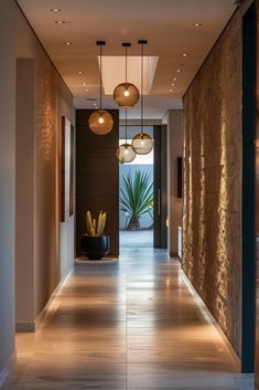 a long hallway with lights hanging from the ceiling and potted plants on either side