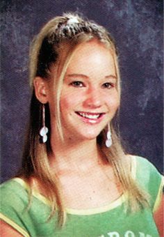 a young woman with long blonde hair and earrings smiling at the camera, wearing a green shirt