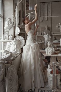 a woman in a white wedding dress standing next to sculptures