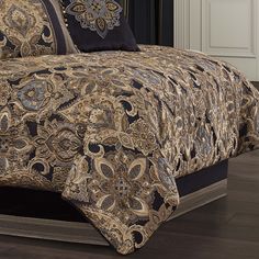 a bed covered in a brown and black bedspread with decorative designs on it