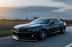 a black camaro is driving down the road