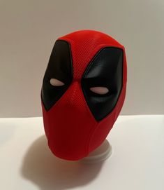 there is a deadpool mask on top of a white stand with the eyes open