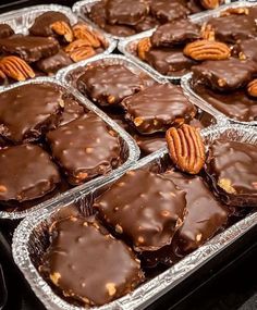 several trays of chocolate covered cookies with pecans on top