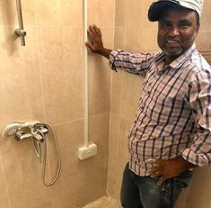 a man standing in front of a shower with his hand on the side of it