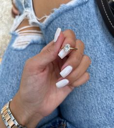 a woman's hand with white nails and a diamond ring on her left finger