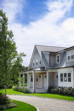 a large gray house sitting on top of a lush green field