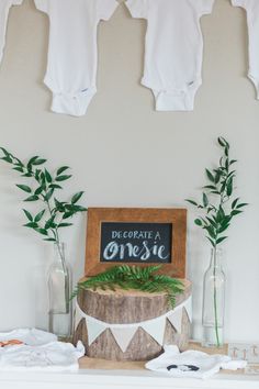 an image of a baby shower with clothes hanging on the wall and plants in vases