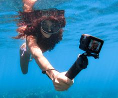 a woman with a camera in her hand under the water while she swims underwater