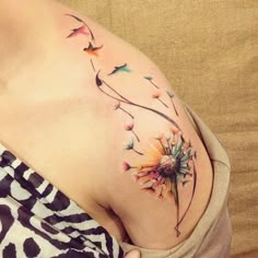 a woman's stomach with a dandelion tattoo on her left side belly