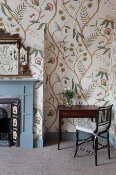 a living room with a fireplace and wallpaper on the walls, along with a chair