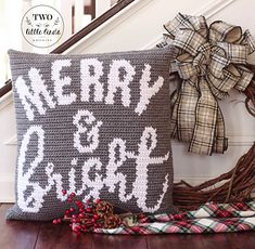 a christmas pillow sitting on top of a wooden floor next to a wreath and bow