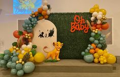 the lion king balloon arch is decorated with balloons and greenery for a baby shower