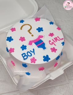 a white cake with pink, blue and yellow frosting has a question mark on it