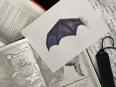 an open book with a bat on it next to some other books and paper clips