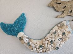 there is a blue bird made out of seashells and other things on the wall