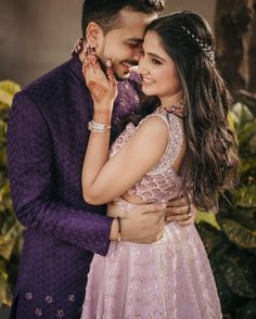 a man in a purple suit and woman in a pink dress are hugging each other