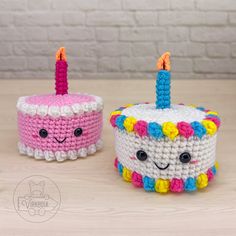 two crocheted birthday cakes sitting on top of a wooden table next to each other