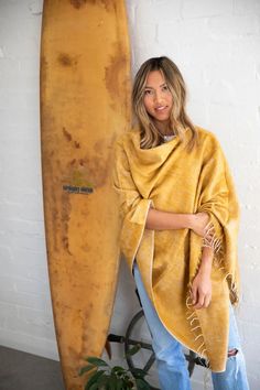 This honey-hued poncho is handwoven in Nepal on majestic wooden looms using a soft, unique yarn and finished with perfectly twisted tassels. Sewn in Western Australia, this piece is perfect for chilly mornings or cool beach evenings. It's easy to style this poncho. Wear it with the v-neck at the front or diagonal for a different look. One size fits most. Approximate size overall is 30 x 74 inches. Wash by hand in cold water and dry with care. Cozy One Size Poncho For Beach, One Size Beach Shawl With Fringe, One Size Tasseled Shawl For The Beach, Beach Shawl With Tassels, Beach Shawl With Tassels One Size, Cozy Fall Poncho For Beach, Bohemian Yellow Scarves For Beach, Beach Poncho Shawl For Fall, Bohemian Yellow Poncho One Size