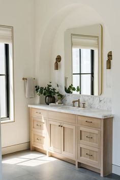 a bathroom with two sinks, mirrors and plants in vases on the counter top