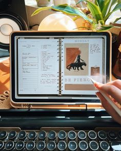 someone is holding an open book in front of a typewriter and typing on it