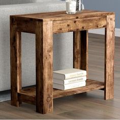 a wooden table with two books and a glass on it in front of a couch