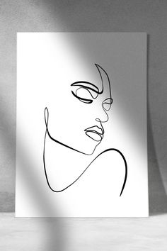 a black and white drawing of a woman's face on a sheet of paper