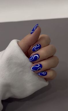 a woman's hand with blue and white nail polish on it, holding onto her arm