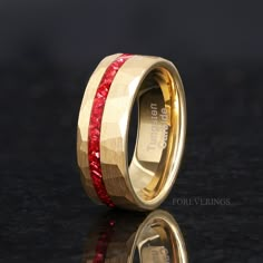 a gold ring with red stones inlayed to the side on a black surface