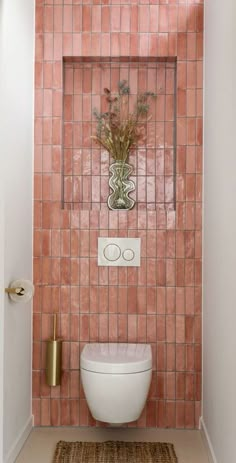 a white toilet sitting in a bathroom next to a pink tiled wall