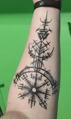 a person with a tattoo on their arm that has a compass and other symbols in it