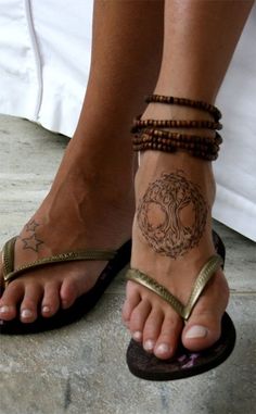 a woman's foot with a tattoo on her left ankle and two bracelets around her ankles