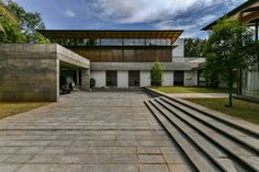 an empty courtyard with steps leading up to the building and trees in the back ground