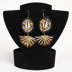 Overview African Earrings with Beaded Frame, Cowrie Shell Center, and Carved from Ox Horn Decorated with Bronze | By Miss Swan
Discover the unique versatility of the 2 in-1 African Earrings with Beaded Frame, a beautifully handcrafted piece that offers two looks in one design.

These earrings feature intricate beadwork framed in an elegant design, making them perfect for both casual and formal occasions.

Whether you’re dressing up for a special event or adding a stylish touch to your everyday wear, the Buy African Earrings with Beaded Frame are a must-have for any jewelry collection.
Why You’ll Love Our African Earrings with Beaded Frame:

 	Versatile 2-in-1 design allows you to wear them in different styles
 	Handcrafted with detailed beading, offering both elegance and tradition
 	Light Beaded Jewelry Earrings, African Earrings, African Beads, Cowrie Shell, Unique Earrings, Different Styles, Elegant Design, Special Events, Bead Work