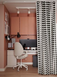 a home office with pink walls and black polka dots on the curtains, along with a white chair