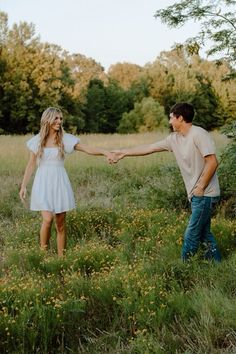 a man and woman holding hands in a field