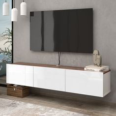 a large flat screen tv mounted to the side of a white entertainment center in a living room