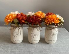 three mason jars with flowers in them on a table