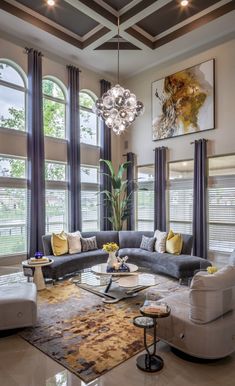 a living room filled with lots of furniture and large windows covered in curtains on either side of the couches